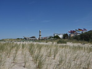 A coastal area with a lighthouse, beach, and buildings with flags. - Ferienwohnung in Rerik for 2 Personen (Rerik)