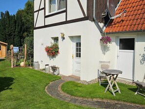 A house with a white exterior, a red-tiled roof, and a garden with a paved path. - Modernes Ferienhaus mit Garten in Kägsdorf (Kägsdorf)