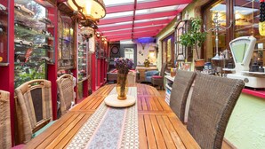A cozy, well-lit café with a wooden table and wicker chairs, a glass ceiling, and a display of vintage cars. - Ferienwohnung mit Wintergarten in Wismar (Wismar)