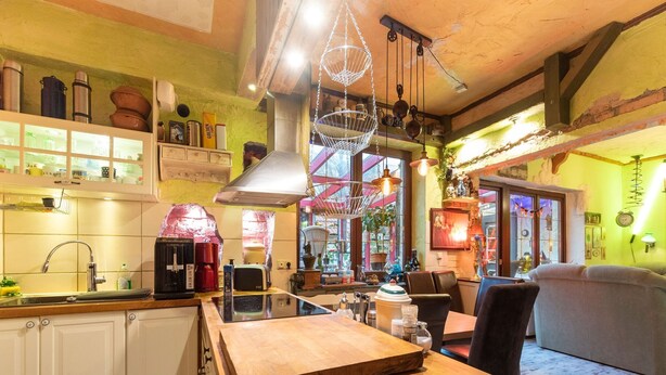 A cozy kitchen with wooden cabinets, a wooden countertop, and a hanging light fixture. - Ferienwohnung mit Wintergarten in Wismar (Wismar)