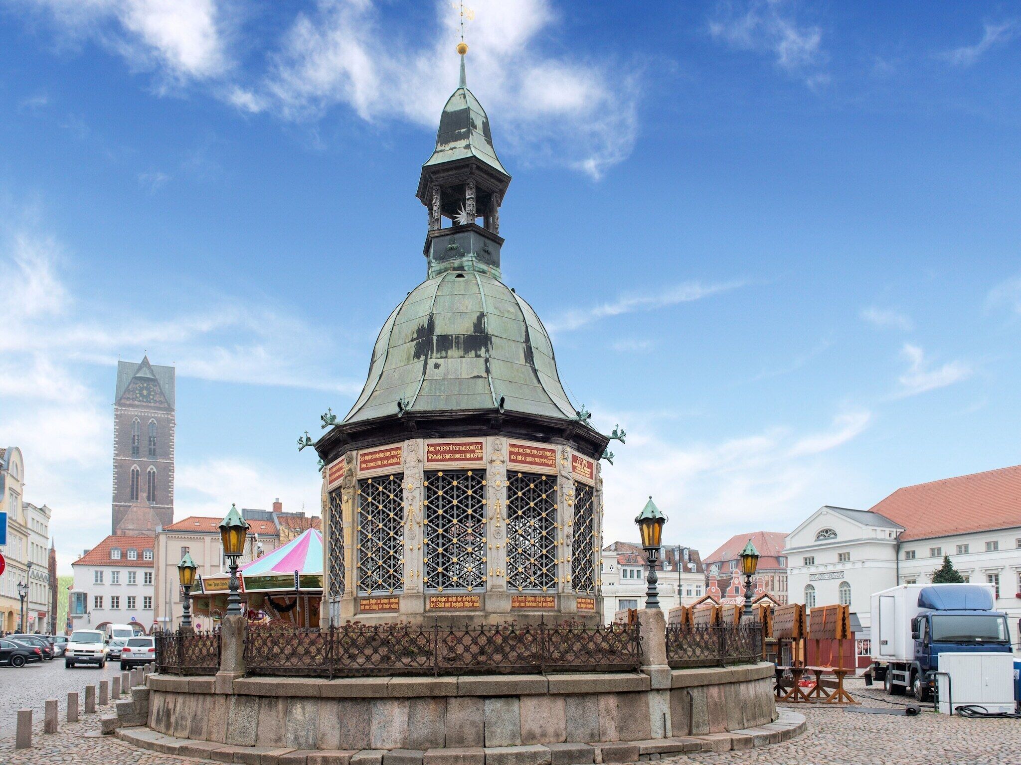 A historic tower with a clock, surrounded by cobblestone streets and traditional buildings.