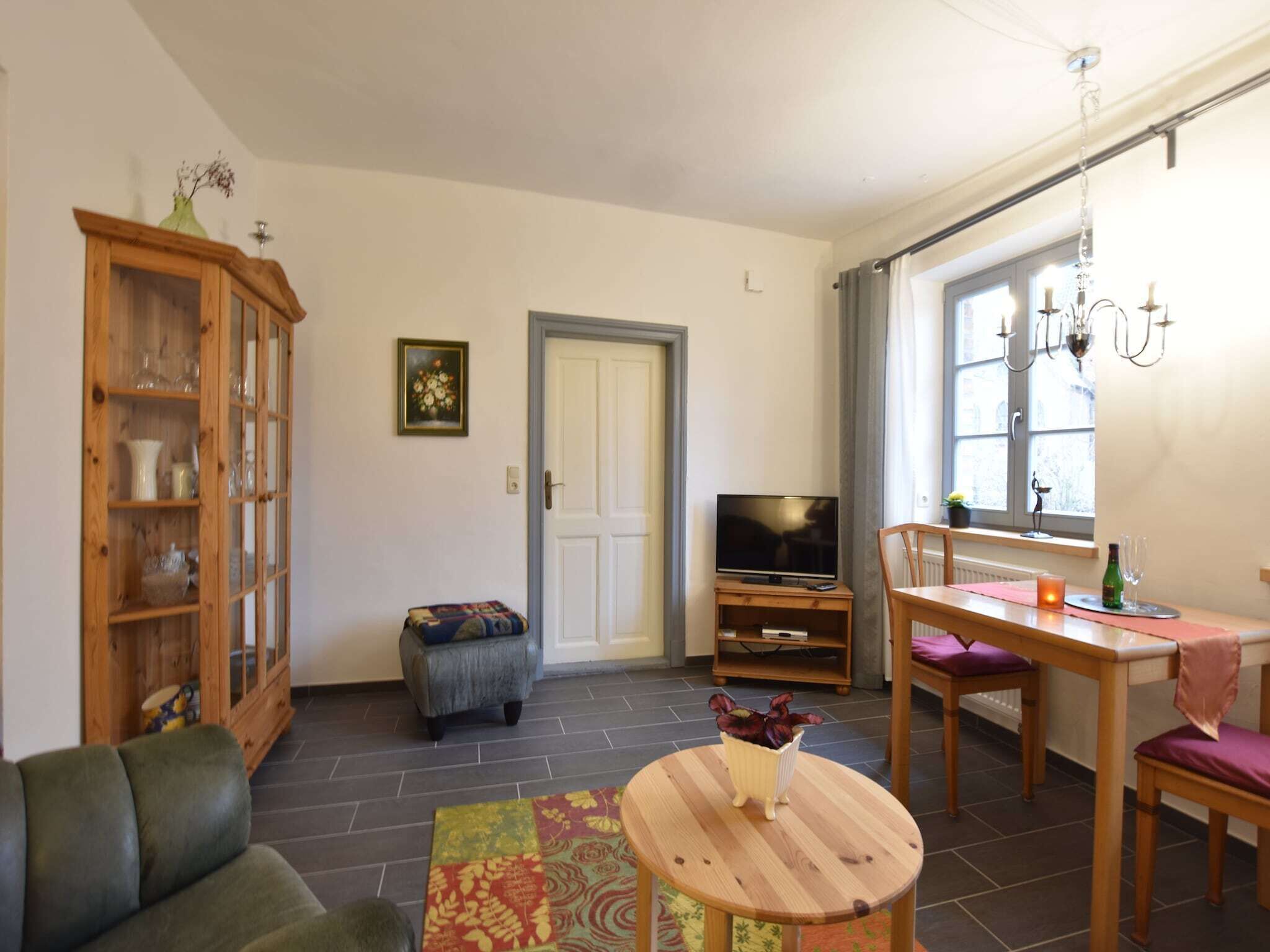 Un salon comprenant un canapé, un meuble en bois, un téléviseur, une table à manger avec des chaises et une fenêtre avec des rideaux.