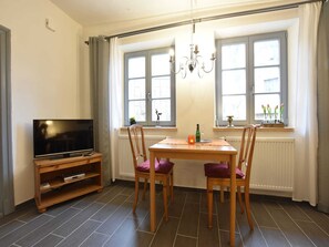A dining area with a table, chairs, a television, and a chandelier. - Wohnung in Klütz nahe Ostseestrand (Klütz)