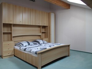 A bedroom with a wooden bed, built-in shelving, and a simple, functional design. - Wohnung in Boddin nahe Ostsee (Walkendorf OT Boddin)