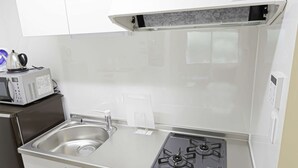 A compact kitchen with white cabinets, a stainless steel sink, a built-in microwave, and a gas stove.