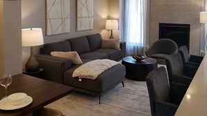 Ein modernes Wohnzimmer mit Sofa, Sesseln, Couchtisch und Kamin.