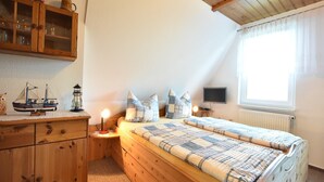 Une chambre confortable avec un lit en bois, une table de chevet, une commode et une fenêtre avec des rideaux.