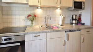 A modern kitchen with light wood cabinets, a stainless steel sink, a microwave, and a coffee maker. - Ferienwohnung in Pepelow nahe der Ostsee (Pepelow)