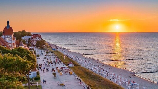 A coastal promenade with a sunset view, featuring a long, open walkway lined with seating areas and a view of the sea. - Ferienwohnung in Pepelow nahe der Ostsee (Pepelow)