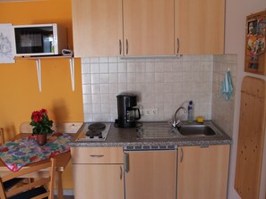 A compact kitchen with wooden cabinets, a microwave, a coffee maker, and a sink. - Komfortable Ferienwohnung in Strandnähe in Rerik (Ostseebad Rerik)