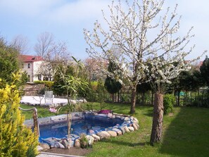 A garden with a swimming pool, a lawn, and a tree with white blossoms. - Komfortable Ferienwohnung in Strandnähe in Rerik (Ostseebad Rerik)