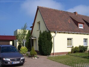 A two-story house with a tiled roof, a driveway, and a parked car. - Komfortable Ferienwohnung in Strandnähe in Rerik (Ostseebad Rerik)