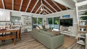 A spacious living area with a wooden ceiling, a green sofa, a dining table, and a TV. - Villa de Paz, STJ 4 BR/2.5B, 2-8 guests Pool Private Renovated AC backup power (St John)