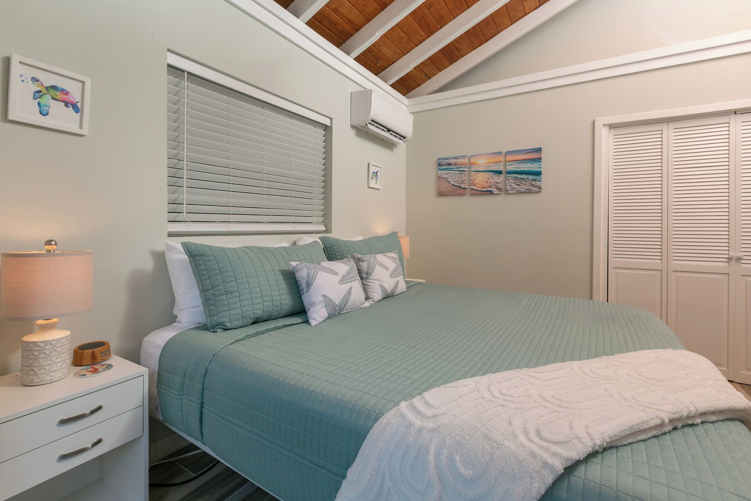 A bedroom with a bed, a nightstand, a lamp, and a window with blinds.