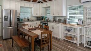 A modern kitchen with white cabinets, stainless steel appliances, and wooden dining furniture. - Villa de Paz, STJ 4 BR/2.5B, 2-8 guests Pool Private Renovated AC backup power (St John)