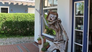 A building with a blue exterior and a wooden sculpture on the porch.