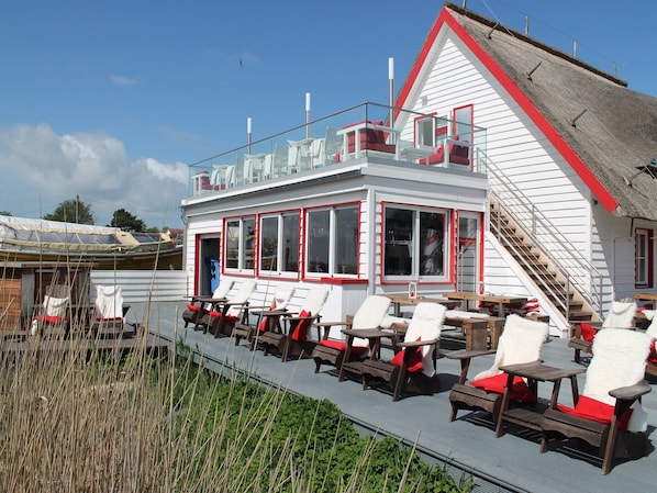 A white building with red trim and a sloped roof. It has multiple windows and a staircase leading to an upper level. - Wohnung in Zingst nahe Ostseestrand (Zingst)