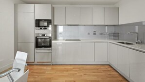 Een moderne keuken met witte kasten, een roestvrijstalen spoelbak en een inbouwoven.