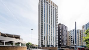 Een modern hoog gebouw met een unieke gevel, omringd door andere woongebouwen.