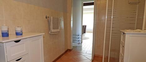 A bathroom with a shower, a sink, and a towel hanging on the wall.