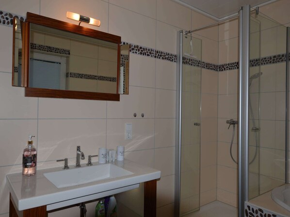 A bathroom with a white sink, a mirror with a wooden frame, and a glass shower enclosure.