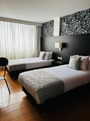 Camera d'albergo con due letti, un comodino, una lampada e una sedia.