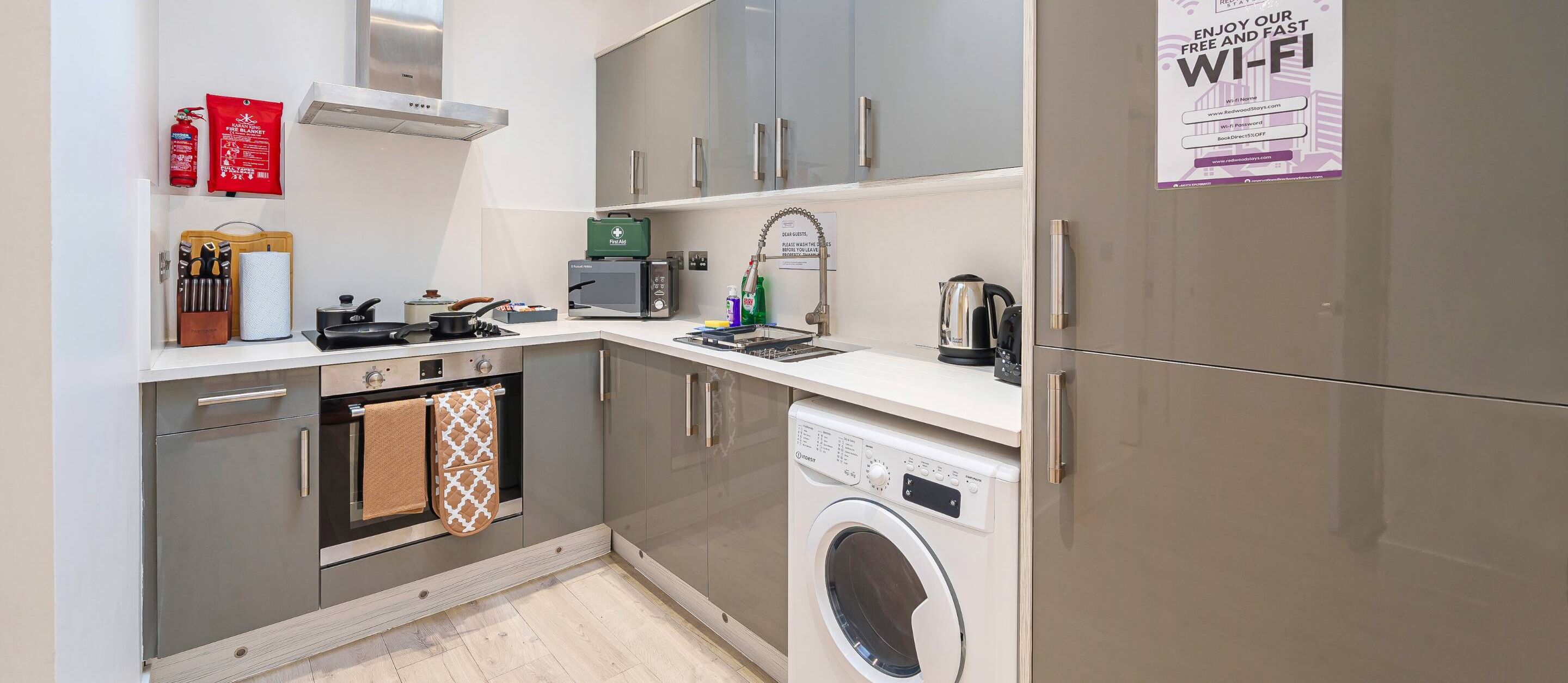 A compact kitchenette with a microwave, toaster, and a washing machine.