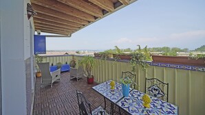 A covered outdoor patio with a tiled table and chairs, potted plants, and a view of the cityscape. - Condominio San Francesco 53 by Wonderful Italy (Desenzano del Garda)