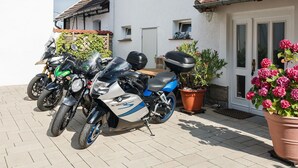 A row of parked motorcycles in front of a house with a tiled roof and a potted plant with pink flowers. - Thale Comfort with Garden (Thale)
