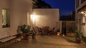 A patio area with a table and chairs, potted plants, and a bench. - Thale Comfort with Garden (Thale)