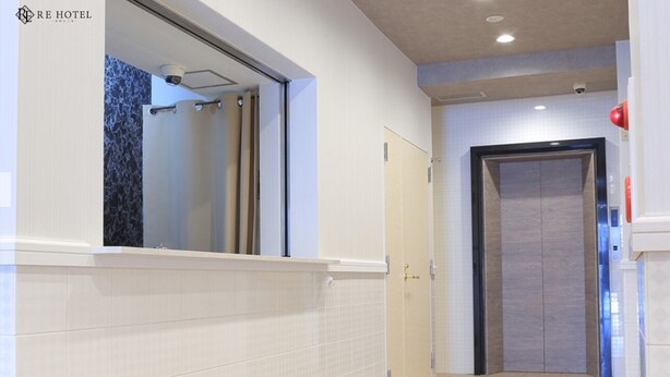 Un baño de hotel con ducha, una puerta y una cámara de seguridad.