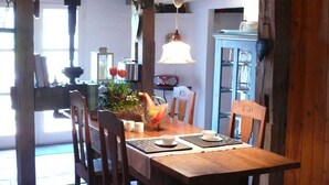 A wooden dining table with chairs, a laptop, and a decorative bird sculpture. - Guest House near Coast (Farve)