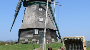A traditional windmill with a thatched roof, wooden structure, and a small door. - Guest House near Coast (Farve)