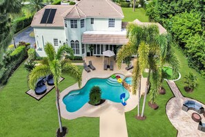 A large house with a swimming pool, outdoor seating, and lush landscaping. - 8BR Entertainers Estate w/ Pool, Games & Theater ! (Coconut Creek)