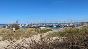 A marina with numerous boats docked, surrounded by sandy terrain and sparse vegetation. - Vacation Home with Pond (Klein Pravtshagen)