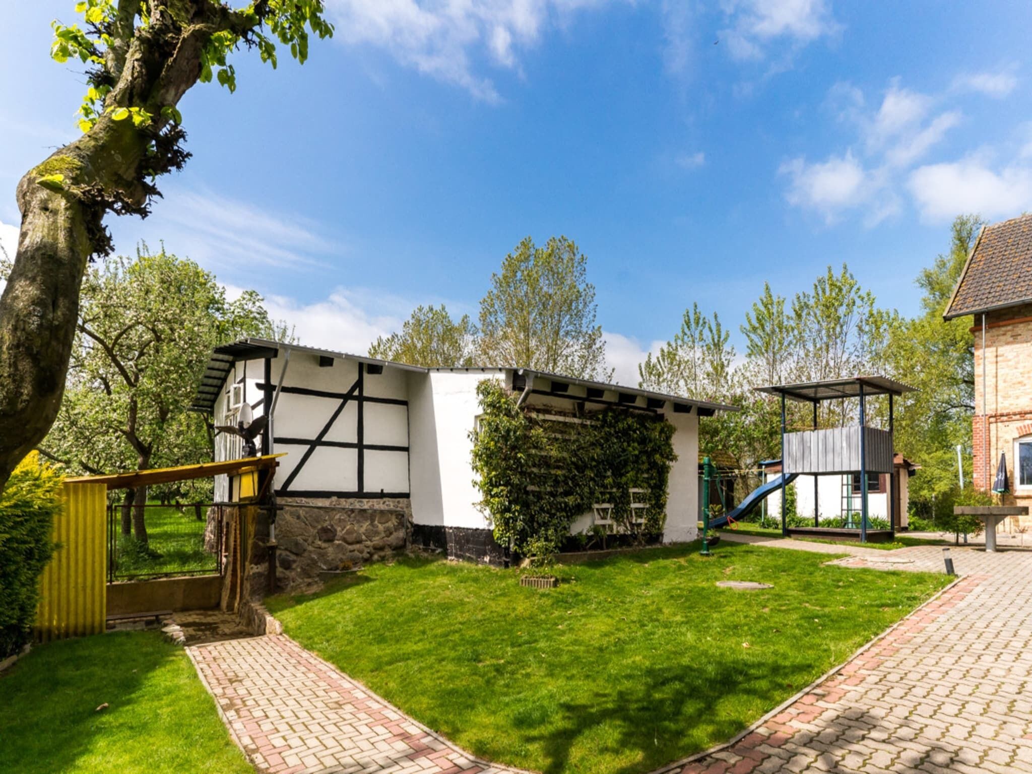 A traditional half-timbered building with a stone foundation, a wooden deck, and a small play structure.