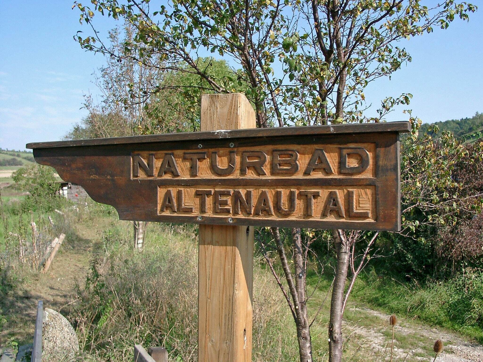 Un cartel de madera con el texto "NATURBAD ALTERNAUTAL" que indica un área natural o sendero.