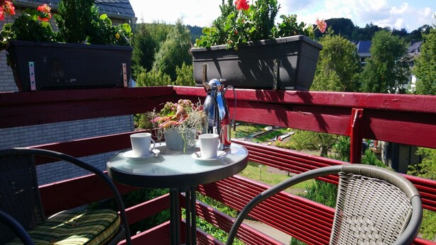 Ein Balkon mit Tisch, zwei Stühlen und einem Blumentopf.