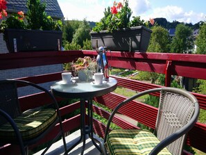Een balkon met een tafel, twee stoelen en een bloempot.