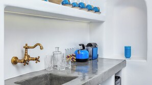 A modern kitchen with a marble countertop, a brass faucet, and a blue kettle.