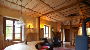 Un intérieur rustique avec des poutres en bois, un comptoir en bois aux lignes courbes, des sièges en cuir et un mur en pierre.