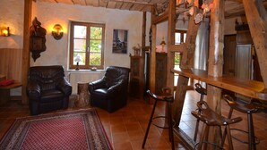 Un intérieur rustique avec des poutres en bois, des fauteuils en cuir, un bar en bois et une grande fenêtre.