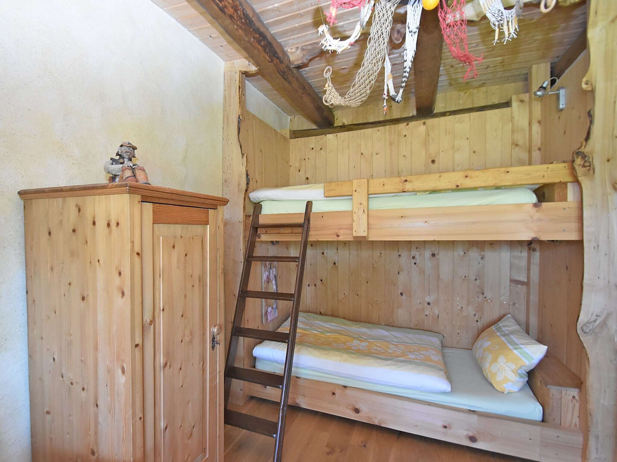 Une cabane en bois avec un lit superposé, une échelle et un petit placard.