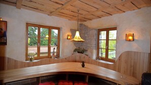 Un banc en bois avec des coussins rouges, un mur en pierre et un plafond en bois.