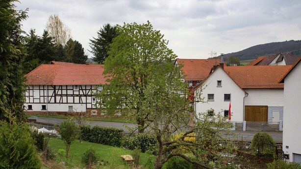 Una casa tradizionale a graticcio con tetto in tegole rosse, circondata da un giardino curato e un piccolo stagno.