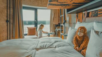 A bedroom with a large bed, a window with curtains, a view of the outside, and a stuffed monkey on the pillows.