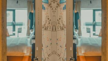 A mirrored view of a room with a bed, a window, and a door.