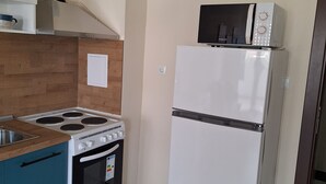 Une cuisine compacte équipée d’une cuisinière, d’un four, d’un four à micro-ondes et d’un réfrigérateur.
