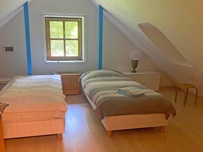 Un dormitorio con dos camas, una ventana, una lámpara y una silla.