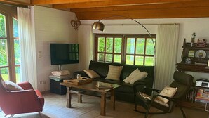 Olohuoneessa on sohva, punainen nojatuoli, puinen sohvapöytä, televisio ja kirjahylly.
